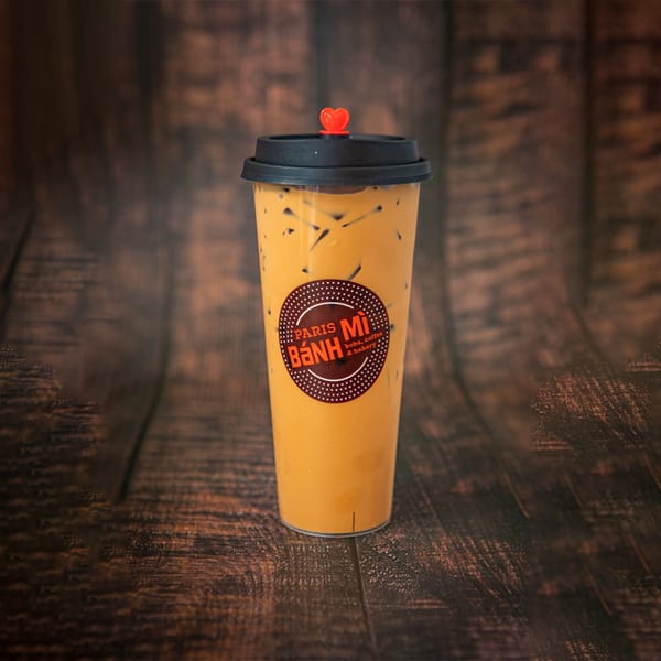 Paris Banh Mi Cary's Thai tea with ice and a red heart straw stopper on a wooden table.