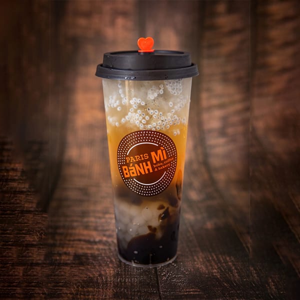 Paris Banh Mi Cary boba tea with chia seeds and dark pearls on a wooden surface.