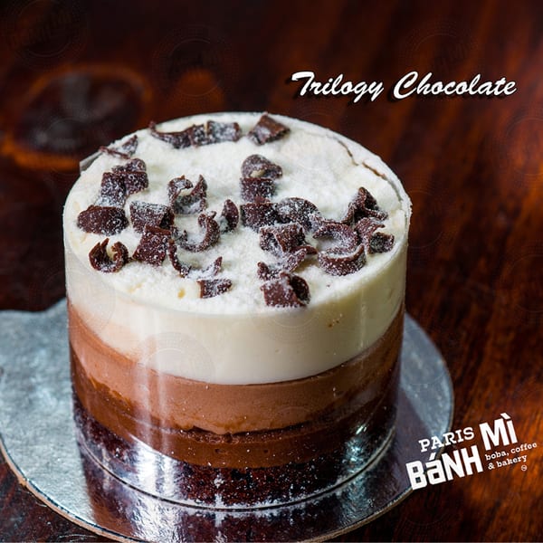 A Trilogy Chocolate cake from Paris Banh Mi, with three layers and chocolate shavings on top.